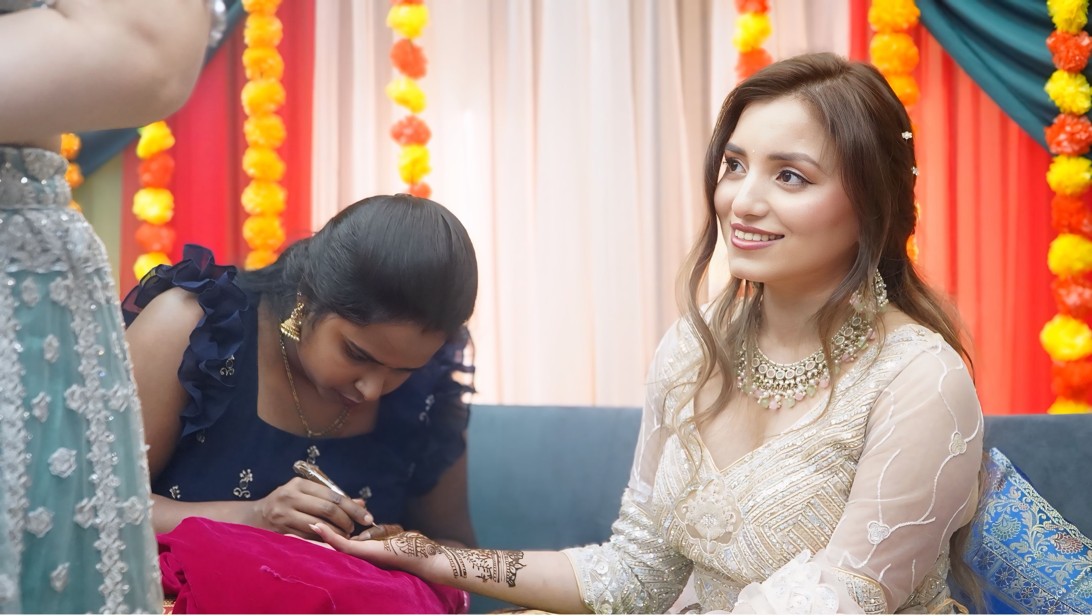 Bride and friend showing henna hands at South Asian wedding celebration
